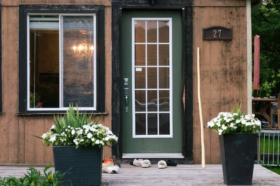 Front door and window of a house with potted flowers